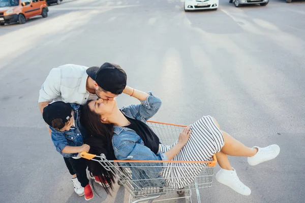 Jeune papa porte maman et fils dans un chariot sur le parking — Photo