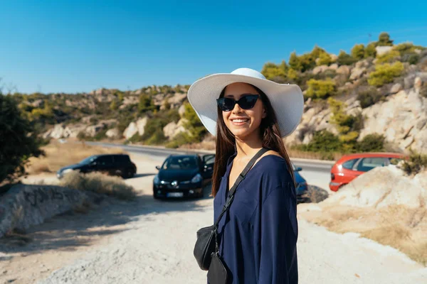 매력적인 여자는 카메라에 포즈입니다 모자와 선글라스에 여자는 백그라운드에서 자동차를 있습니다 — 스톡 사진