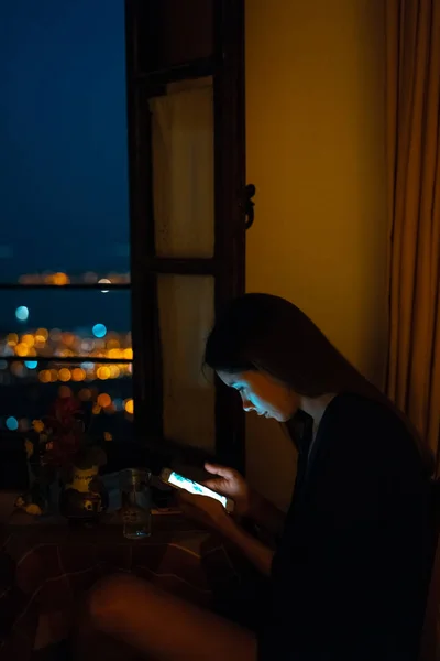 Kobieta za pomocą smart phone dla online w domu w godzinach wieczornych — Zdjęcie stockowe