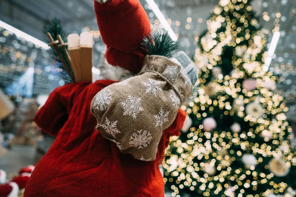 Papai Noel por trás com saco de presente no fundo da árvore de Natal bokeh . — Fotografia de Stock