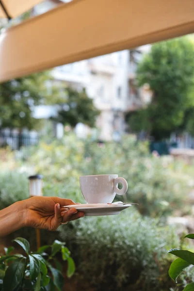 Mano de mujer sosteniendo plato blanco y taza de café caliente — Foto de Stock