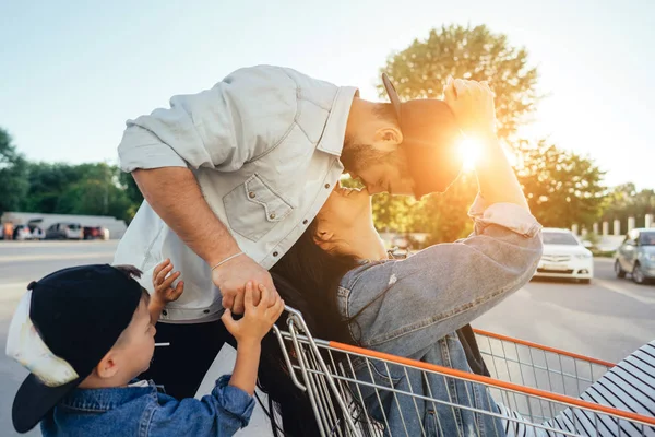 Young dad carries mom and son in a cart on the parking lot