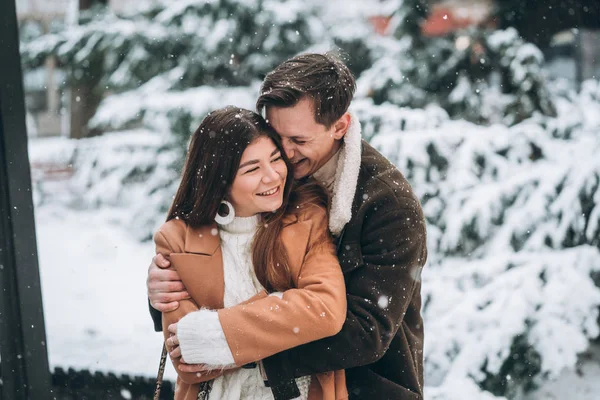 Ung kille kramar en vacker flicka i snöig park — Stockfoto