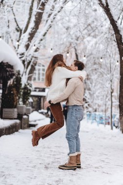 Genç adam bir güzel kız onun kollarında tutar. İki kazak içinde.