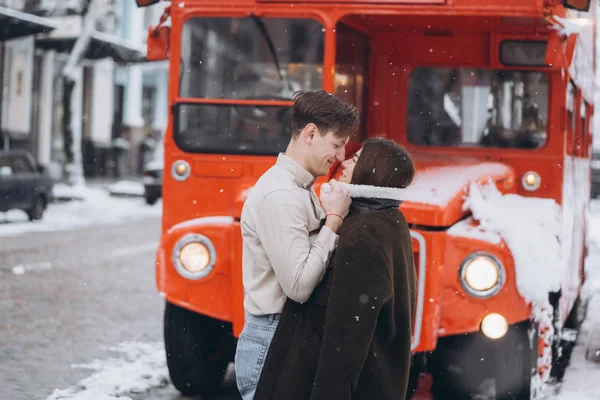 Jovem cara aquece sua linda menina com jaqueta em uma rua nevada — Fotografia de Stock