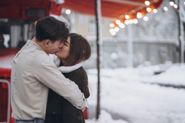 Jovem cara e bela menina beijo em uma rua nevada — Fotografia de Stock