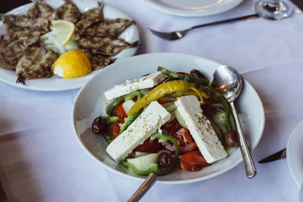 Ikan goreng kecil dengan lemon dan salad Yunani — Stok Foto