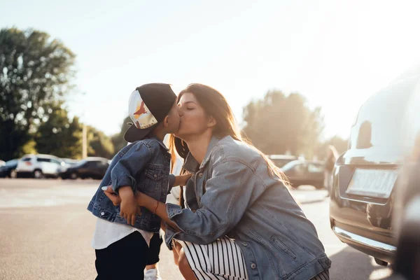 Um menino beija sua amada mãe no estacionamento — Fotografia de Stock
