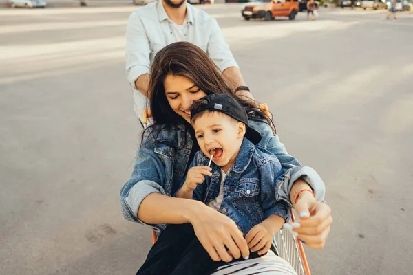 Молодой отец таскает маму и сына в повозке на парковке — стоковое фото