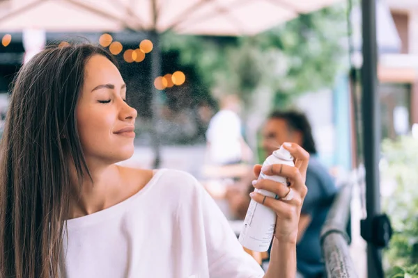 He girl is spraying herself with a spray — Stock Photo, Image