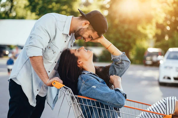 Un tipo guapo lleva a su novia en el carro. Guy besa a su novia —  Fotos de Stock