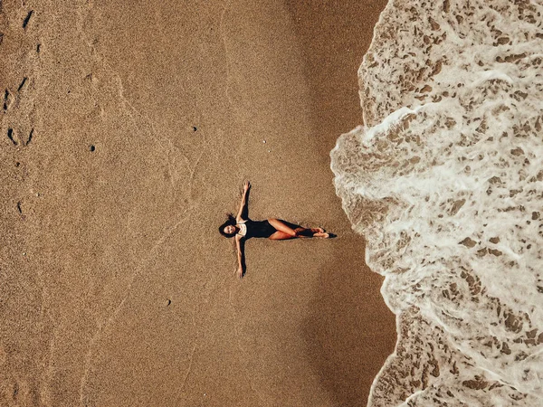 Widok z lotu ptaka top młoda kobieta, leżąc na plaży piasek i fale — Zdjęcie stockowe