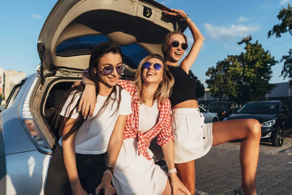 Drei junge Frauen posieren auf dem Parkplatz für die Kamera. — Stockfoto