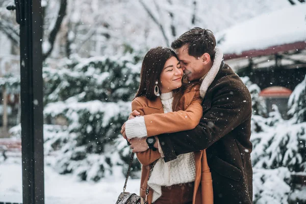 Ung kille kramar en vacker flicka i snöig park — Stockfoto