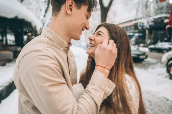 年轻的家伙和美丽的女孩亲吻在一个雪公园。情侣穿着毛衣. — 图库照片