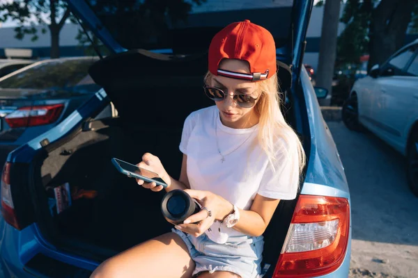 A young, sexy girl sitting in the trunk of the car. — Stock Photo, Image