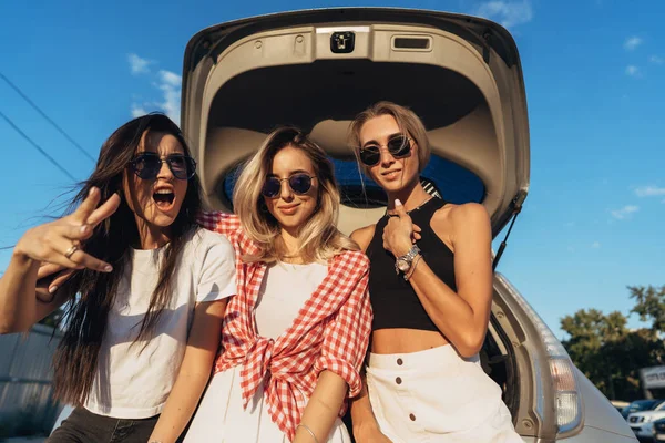 Drie jonge vrouw poseren voor de camera de parkeerplaats. — Stockfoto