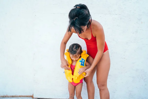 Une mère aidant sa fille avec son gilet de sauvetage — Photo