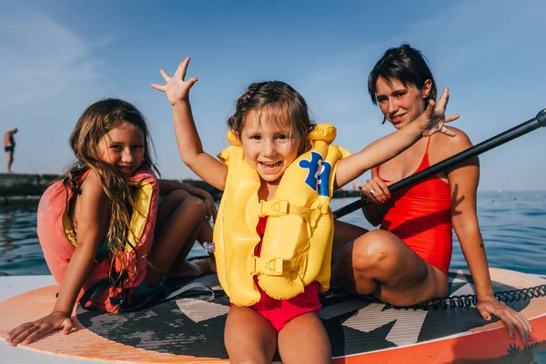 Mother with two daughters stand up on a paddle board — Stock Photo, Image