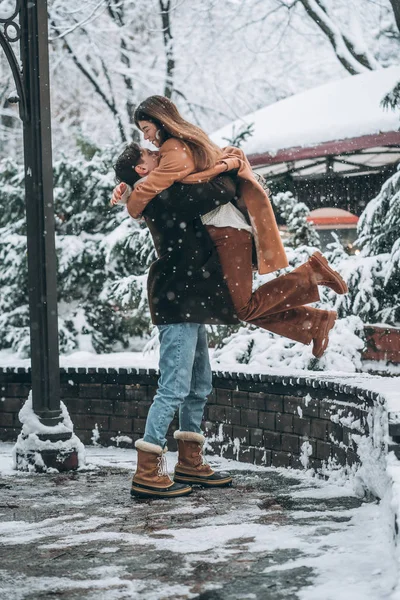 Jovem cara segura uma linda garota em seus braços — Fotografia de Stock