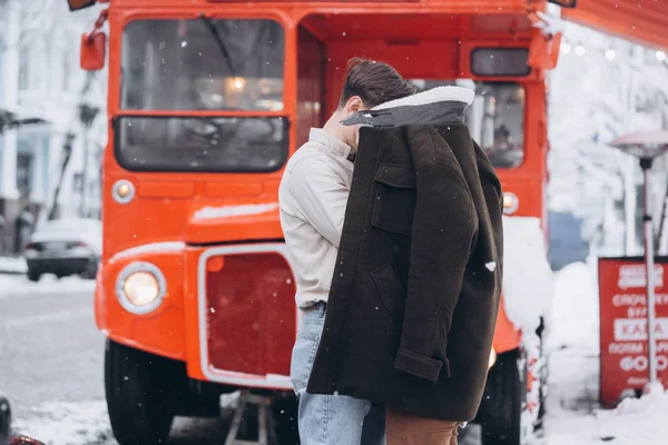 Jovem cara aquece sua linda menina com jaqueta em uma rua nevada — Fotografia de Stock