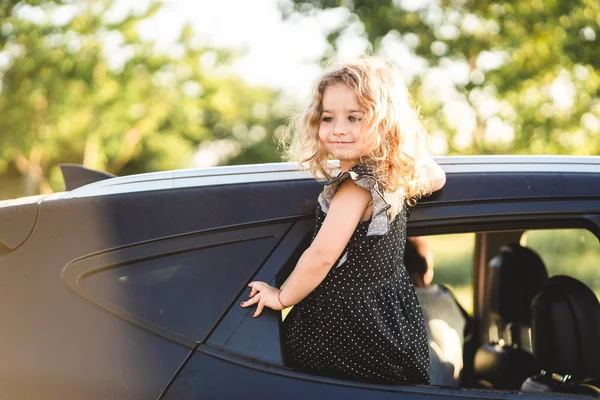 Seorang gadis kecil sedang duduk di pintu mobil — Stok Foto