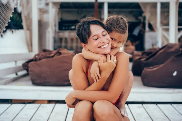 Ung mor ger dotter piggyback rida på stranden — Stockfoto