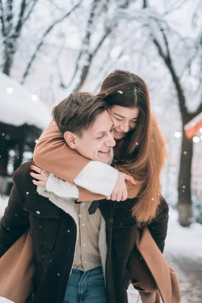 Belo jovem casal se divertindo em uma rua nevada — Fotografia de Stock