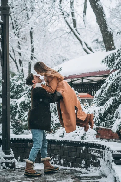 Genç adam bir güzel kız onun kollarında tutar.