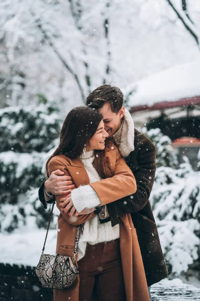 Молодий хлопець обіймає красиву дівчину в сніжному парку — стокове фото