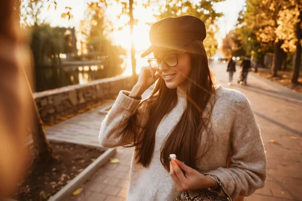 Красивая молодая девушка слушает музыку в парке через беспроводной наушник — стоковое фото