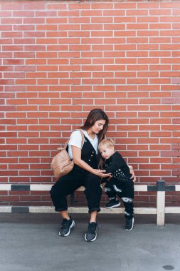 Anne ve genç oğlu tuğla üzerinde poz arka plan duvar