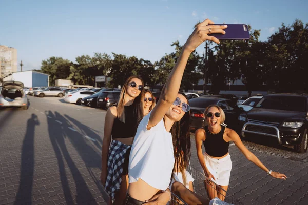 Cinque ragazze si divertono con un carrello del supermercato in un parcheggio — Foto Stock