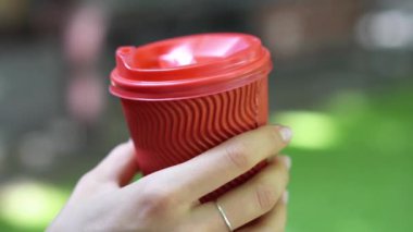 Kadın açık havada kırmızı plastik bir kap onun elinde tutan.