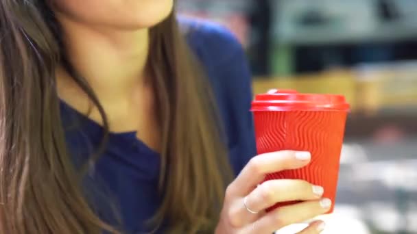Жінка на відкритому повітрі тримає червону пластикову чашку в руці . — стокове відео
