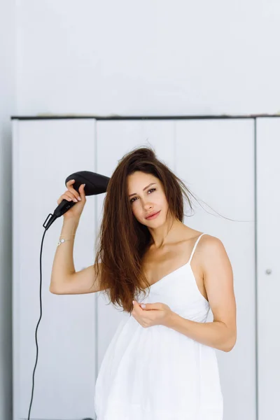 Beyaz arka plan üzerinde saç kurutma makinesi ile kurutma bornoz kadında — Stok fotoğraf