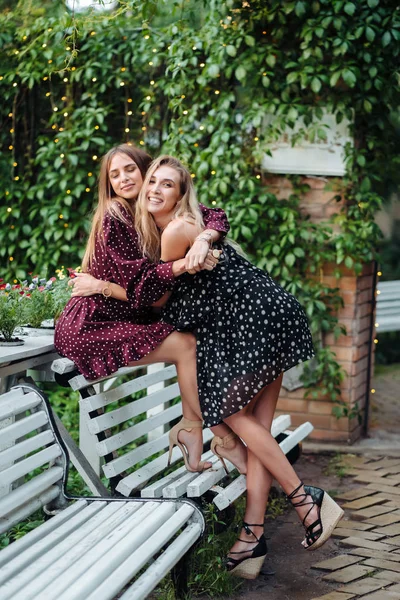 Two girls in the park hugging on the bench — Stock Photo, Image