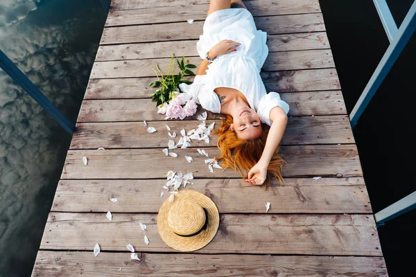 Ahşap zemin üzerinde beyaz elbiseli çekici genç hipster kadın yatıyor. — Stok fotoğraf
