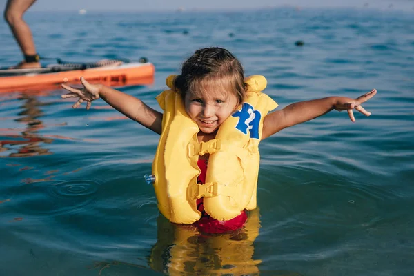 Petite fille dans un gilet de sauvetage se baigner dans la mer . — Photo