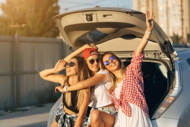 Araba park kamera için poz üç genç kadın.