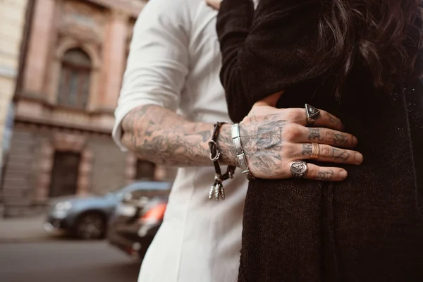 A mão de homem em tatuagens e jóias abraça uma cintura de meninas . — Fotografia de Stock