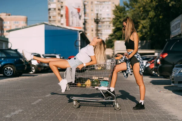 Dvě mladé dívky v sluneční brýle pózuje pro kameru na parkování. — Stock fotografie