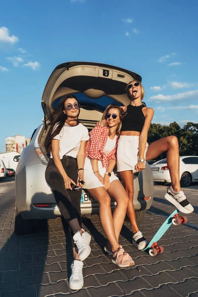 Tiga wanita muda berpose untuk kamera tempat parkir mobil . — Stok Foto