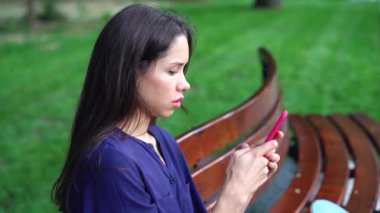 Tezgah ve arka plan üzerinde park smartphone kullanarak kadın oturur.