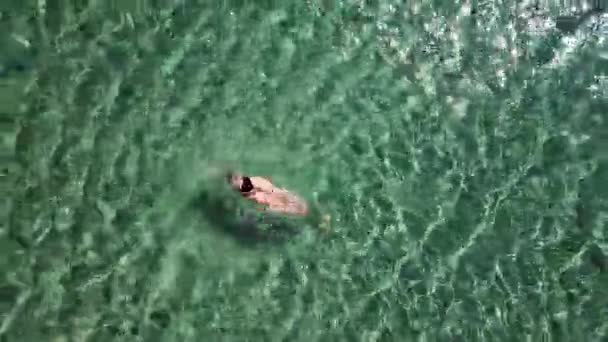 Mädchen im schwarzen Badeanzug schwimmt im Meer. — Stockvideo