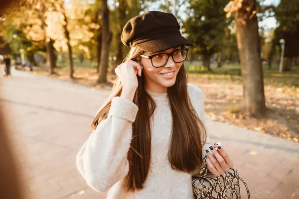 Hermosa joven escuchando música en el parque a través de un auricular inalámbrico — Foto de Stock