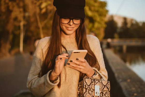 Uma jovem morena de cabelos longos lê uma mensagem SMS . — Fotografia de Stock