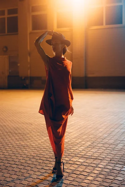 A jovem, menina atraente em um chapéu posa para a câmera à noite — Fotografia de Stock