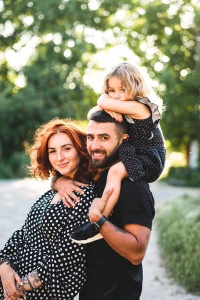 Glückliche Eltern mit einer kleinen Tochter auf den Schultern — Stockfoto