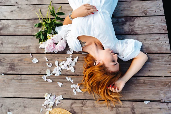 Attractive young hipster woman in white dress lies on the wooden floor. — Stock Photo, Image